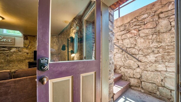 A purple door with a keypad lock, a stone wall, and a staircase leading to an upper level. - The perfect spot in Salida - F Street Hideaway! (Salida)