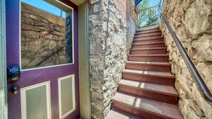 A staircase leading to a stone wall with a purple door featuring a security camera and a peephole. - The perfect spot in Salida - F Street Hideaway! (Salida)