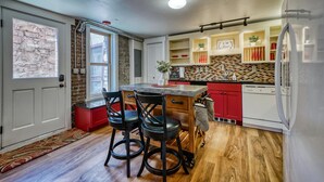 A compact kitchen with a central island, red cabinets, and a stone backsplash. - The perfect spot in Salida - F Street Hideaway! (Salida)