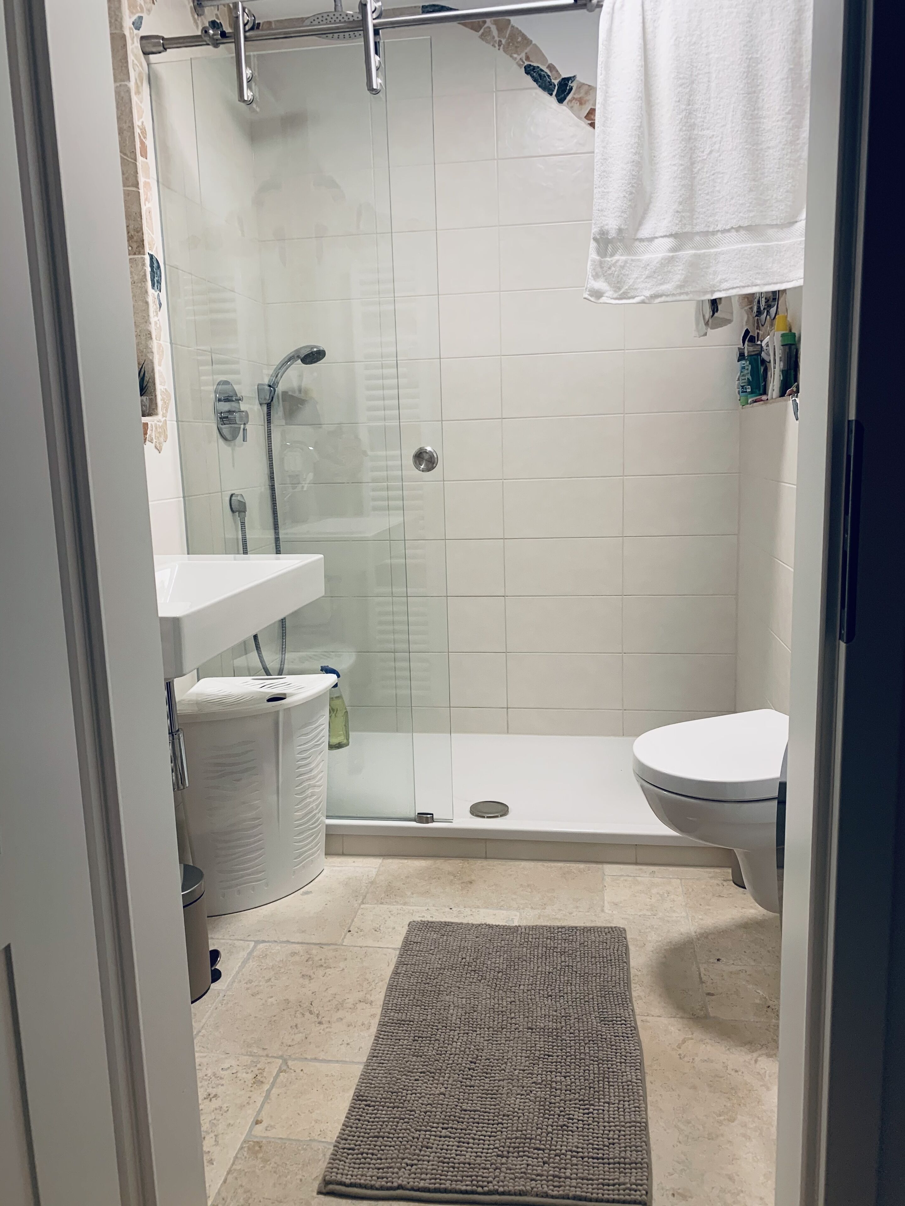 A bathroom with a glass-enclosed shower, a white sink, and a toilet.