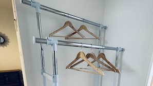 A metal clothing rack with wooden hangers against a wall in a room with tiled flooring. - Modern vacation apartment "La Fredo" near Lake Starnberg, 5 minutes' walk to public transport (Wolfratshausen)