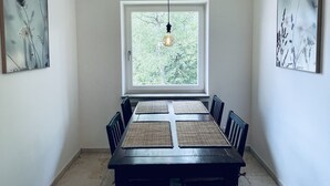 A dining area with a rectangular table, four chairs, and a hanging light fixture. - Modern vacation apartment "La Fredo" near Lake Starnberg, 5 minutes' walk to public transport (Wolfratshausen)