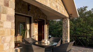 An outdoor patio with stone flooring and wicker furniture. - Tree of Life Vanvilas Riveredge (Ramnagar)