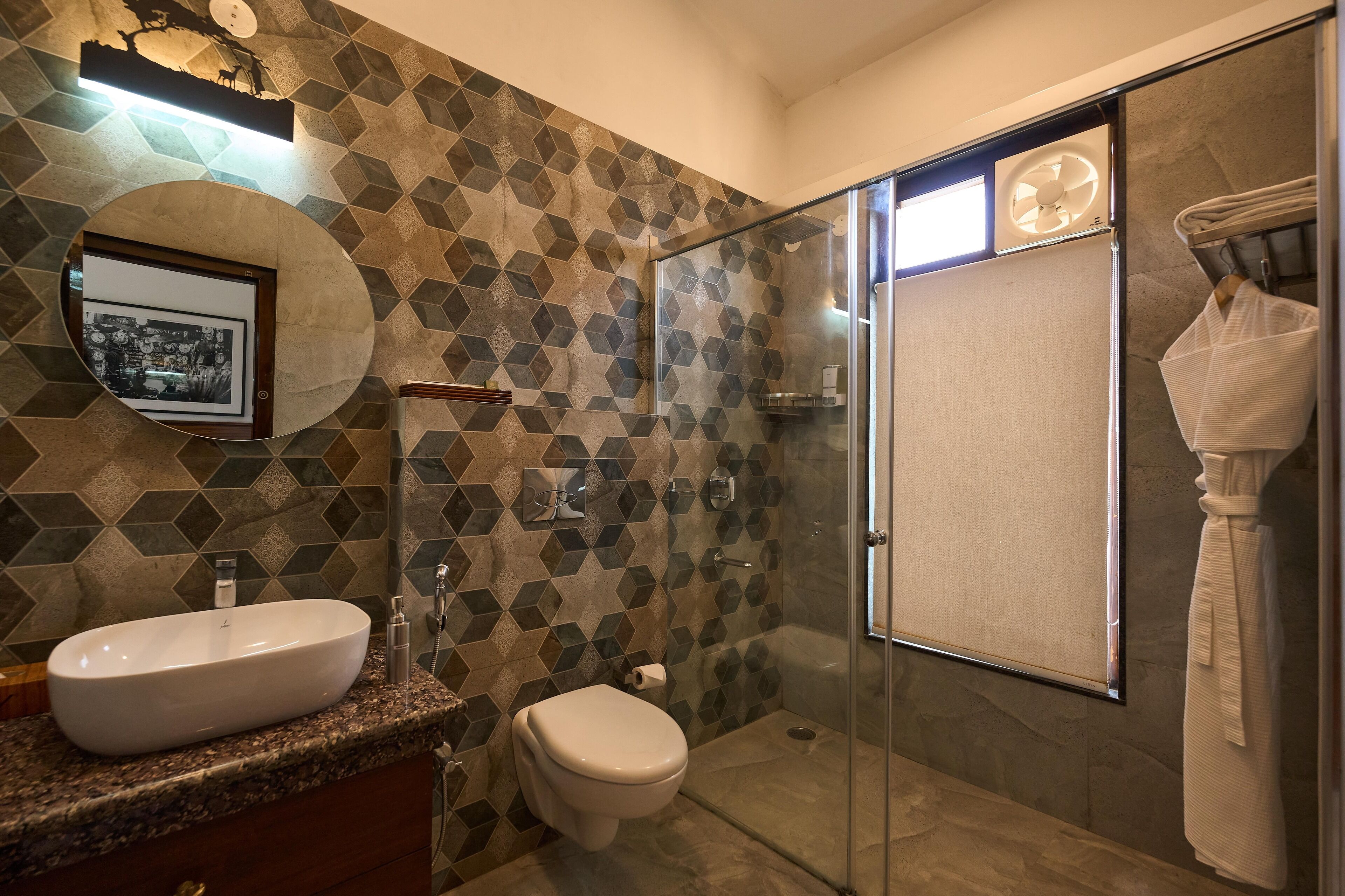 Un bagno moderno con pannelli decorativi in piastrelle geometriche, un lavabo freestanding, un water e una cabina doccia con pareti in vetro.