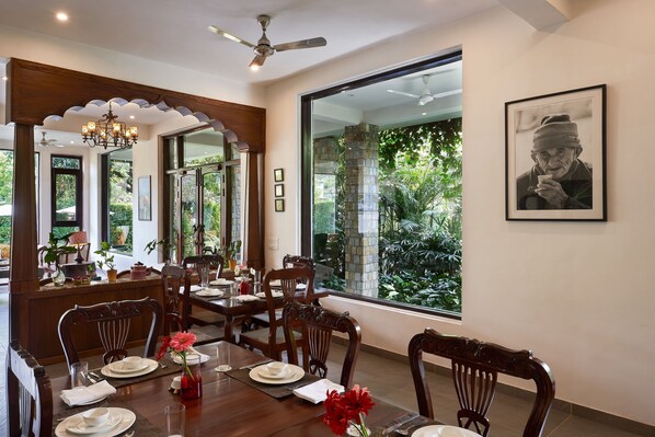 A dining area with wooden furniture, a chandelier, and a large window with a view of greenery.