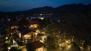 A well-lit residential area with multiple houses, a stone pathway, and a lawn. - Tree of Life Vanvilas Riveredge (Ramnagar)