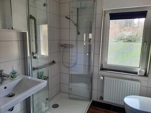 Un baño moderno con cabina de ducha de vidrio, un lavabo blanco y un inodoro.