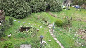 Un jardín con un camino, un estanque pequeño y diversas plantas.