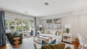 A spacious living room with a sofa, armchairs, a coffee table, and a dining area.