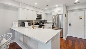 A modern kitchen with white cabinetry, stainless steel appliances, and a central island.