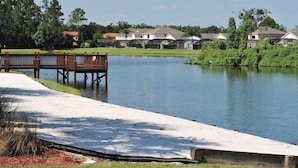 A waterfront property with a sandy beach, a wooden dock, and houses in the background. - Ref 502. Lake Berkley. Stunning Villa, own pool. Near Disney (Kissimmee)