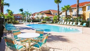 A swimming pool with lounge chairs and tables, surrounded by palm trees and buildings with red roofs. - Ref 502. Lake Berkley. Stunning Villa, own pool. Near Disney (Kissimmee)