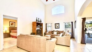 A spacious living room with two beige sofas, a wooden cabinet, and a ceiling fan. - Ref 502. Lake Berkley. Stunning Villa, own pool. Near Disney (Kissimmee)