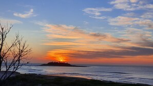 A sunset over a beach with a distant island. - The Sandbar (Lake Conjola)