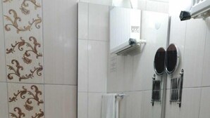 Une petite salle de bain avec des toilettes, un lavabo et un miroir. Il y a un porte-serviettes au-dessus du lavabo et un sèche-cheveux fixé au mur.