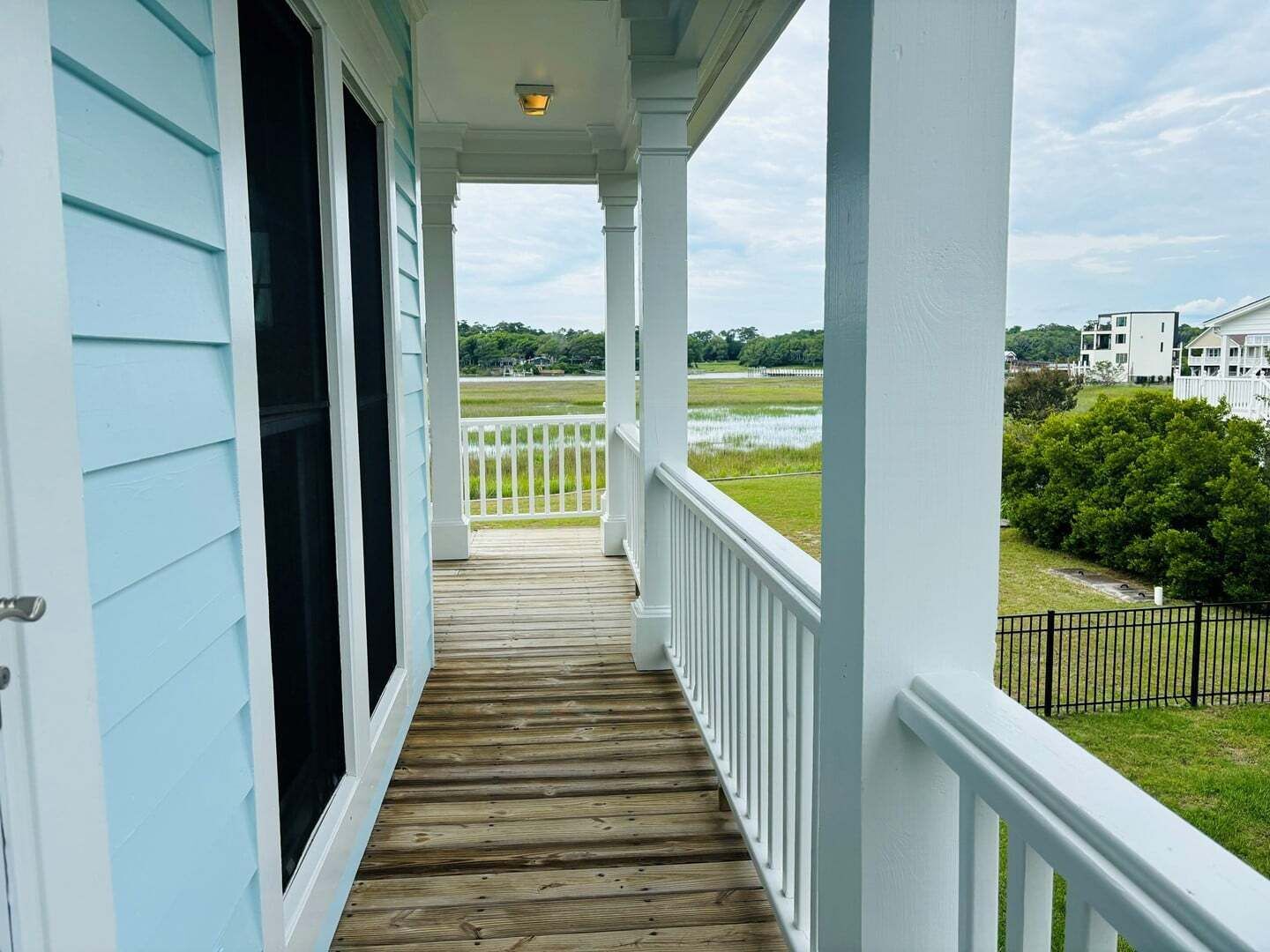 A covered porch with a view of a grassy area and a body of water.