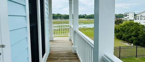 A covered porch with a view of a grassy area and a body of water.