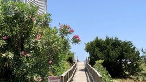 A wooden pathway leading to a building with a sign indicating private property. - Experience coastal charm at No Egrets, a spacious 3-bedroom retreat in Holden Beach. (Holden Beach)
