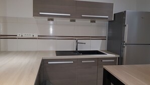 A modern kitchen with a stainless steel refrigerator, a built-in sink, and wooden cabinets.