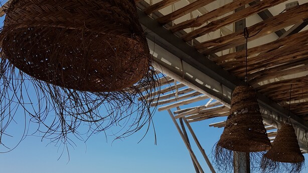 A beachside restaurant with white umbrellas and wicker furniture.