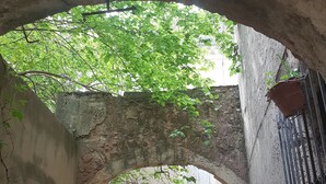 An arched stone structure with a window and a barred door.