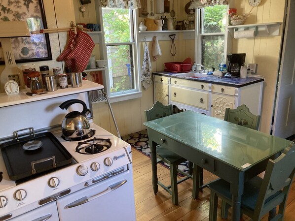 A kitchen with a stove, sink, and a dining table with chairs.