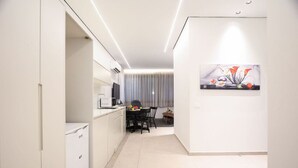 Eine moderne Küche mit weißen Schränken, einem Essbereich mit Tisch und Stühlen sowie einem Bild an der Wand.