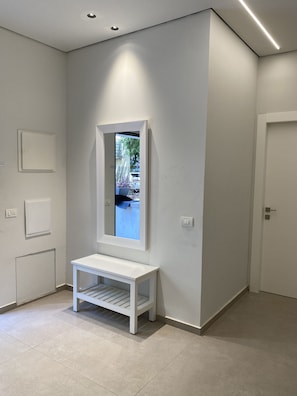 Relax in a serene hallway with a comfortable bench and a large mirror.