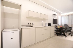 A compact kitchen with a refrigerator, microwave, kettle, and a dining area with chairs and a table. - Cozy Apartment in the Heart of Tel Aviv (Tel Aviv)