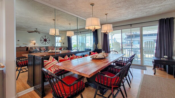 A spacious dining area with a large wooden table, red upholstered chairs, and pendant lighting. - Fun, Chill, and Coastal Comfort at Hoot (Topsail Beach)