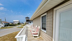 A house with a porch featuring rocking chairs, a view of the street, and a neighboring building with a tower. - Fun, Chill, and Coastal Comfort at Hoot (Topsail Beach)