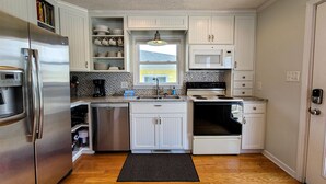 A modern kitchen with white cabinetry, stainless steel appliances, and a black mat on the floor. - Fun, Chill, and Coastal Comfort at Hoot (Topsail Beach)