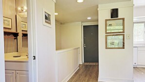 A hallway with wooden flooring, white walls, and a door at the end. - Townhouse Style Condo, Beach Access Across Road, Pool, Grilling Area, Elevator (Pawleys Island)