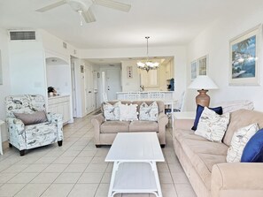 A living room with a beige sofa, a patterned armchair, and a white coffee table.