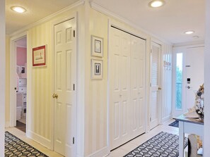 A hallway with white doors, a patterned rug, and a door with a beach-themed decoration.