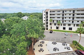 A multi-story building with a parking lot, outdoor seating area, and a flag.