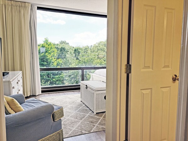 A room with a large window, a sofa, a small table, and a door.