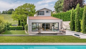 Une maison moderne dotée d’une piscine, d’un patio avec mobilier d’extérieur et d’un jardin bien entretenu.