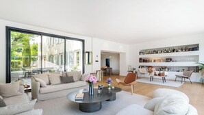 Un salon spacieux avec une grande fenêtre, une table basse ronde et un canapé moderne.
