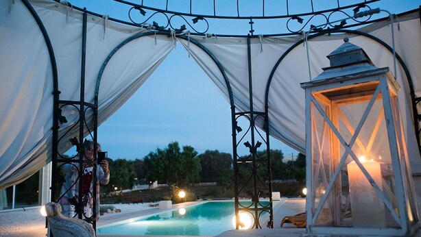 An outdoor pool area with a covered seating area and a lantern. - Lamia from the 5 chimneys (San Michele Salentino)