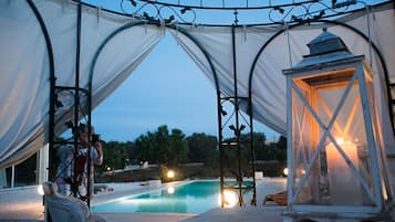Un espace piscine extérieur doté d’un coin salon couvert et d’une lanterne.