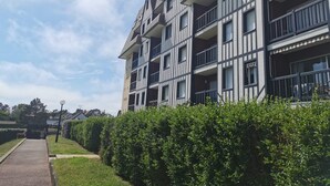 Een meerlaags woongebouw met balkons, een verhard pad en een verzorgde haag.