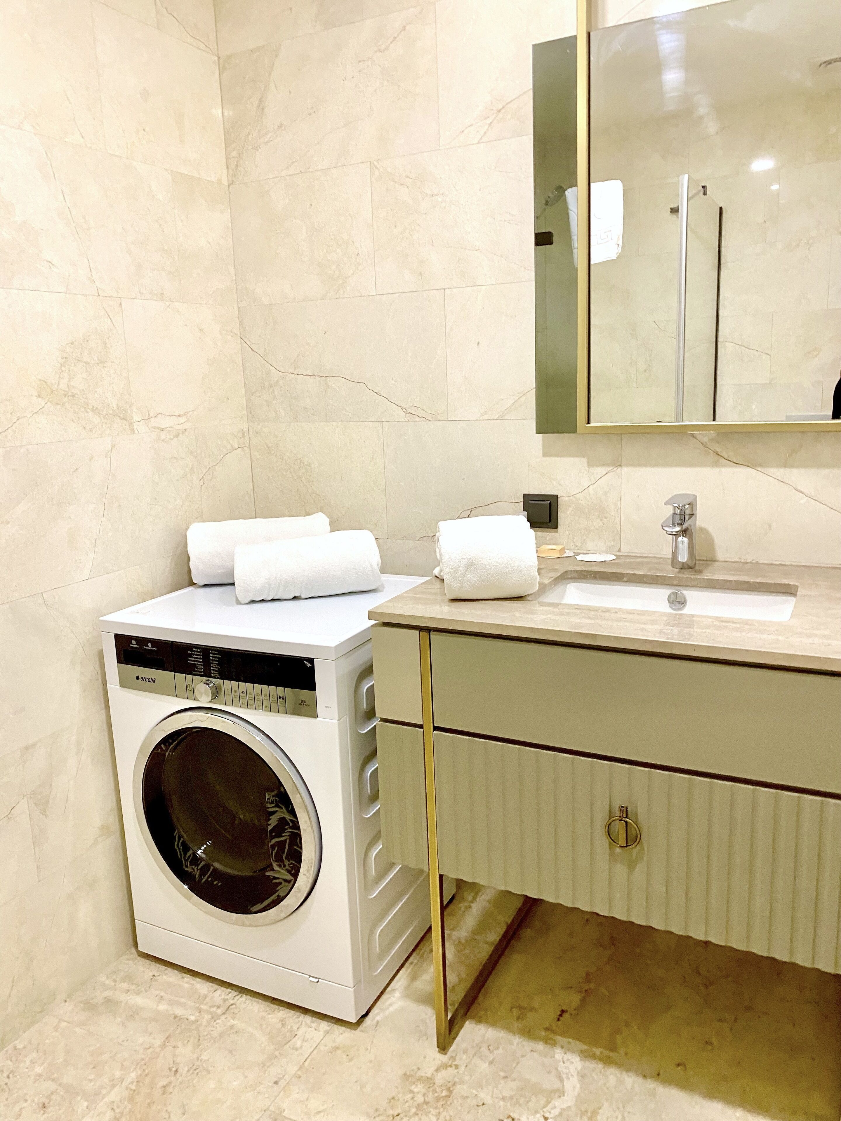 Un baño moderno con lavadora integrada, un lavabo y un espejo sobre el mueble.