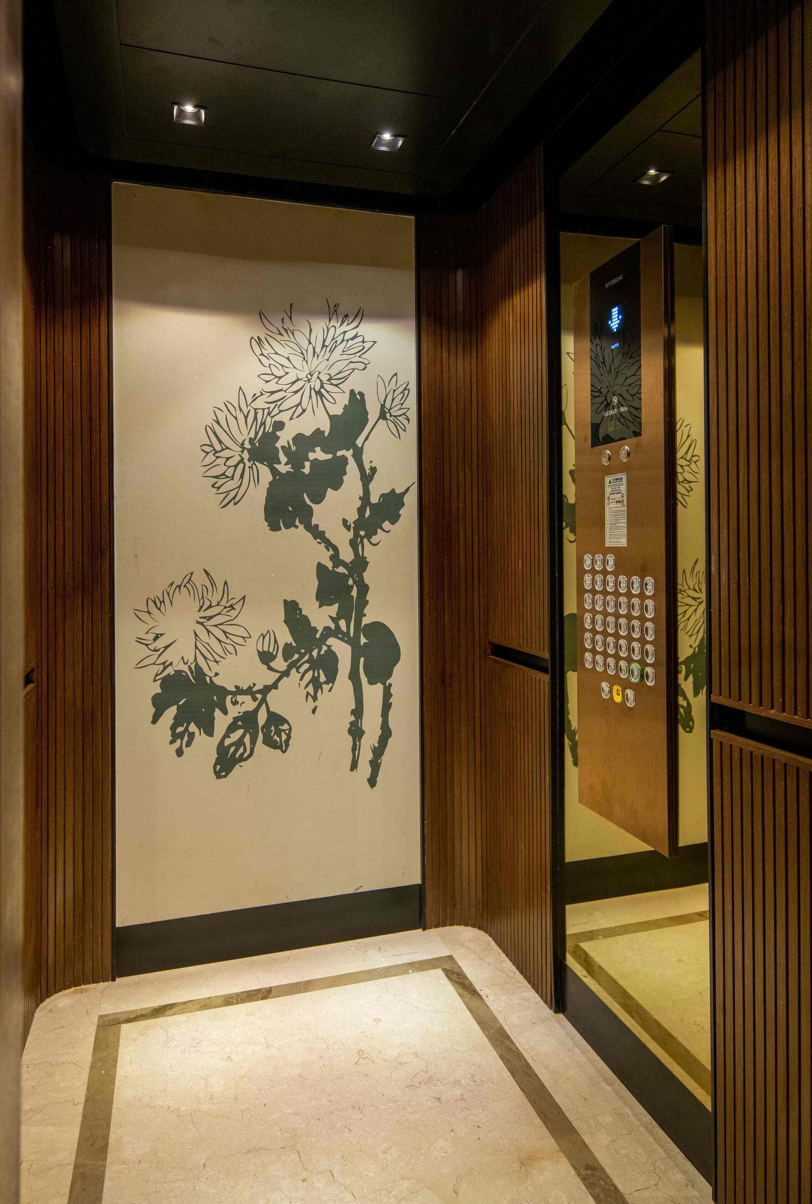 An elevator interior with a floral wall design, a control panel with buttons, and a wooden panel design.