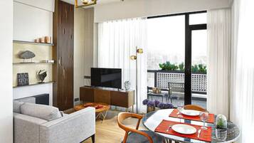 A modern living room with a sofa, TV, and dining area with chairs and a table.