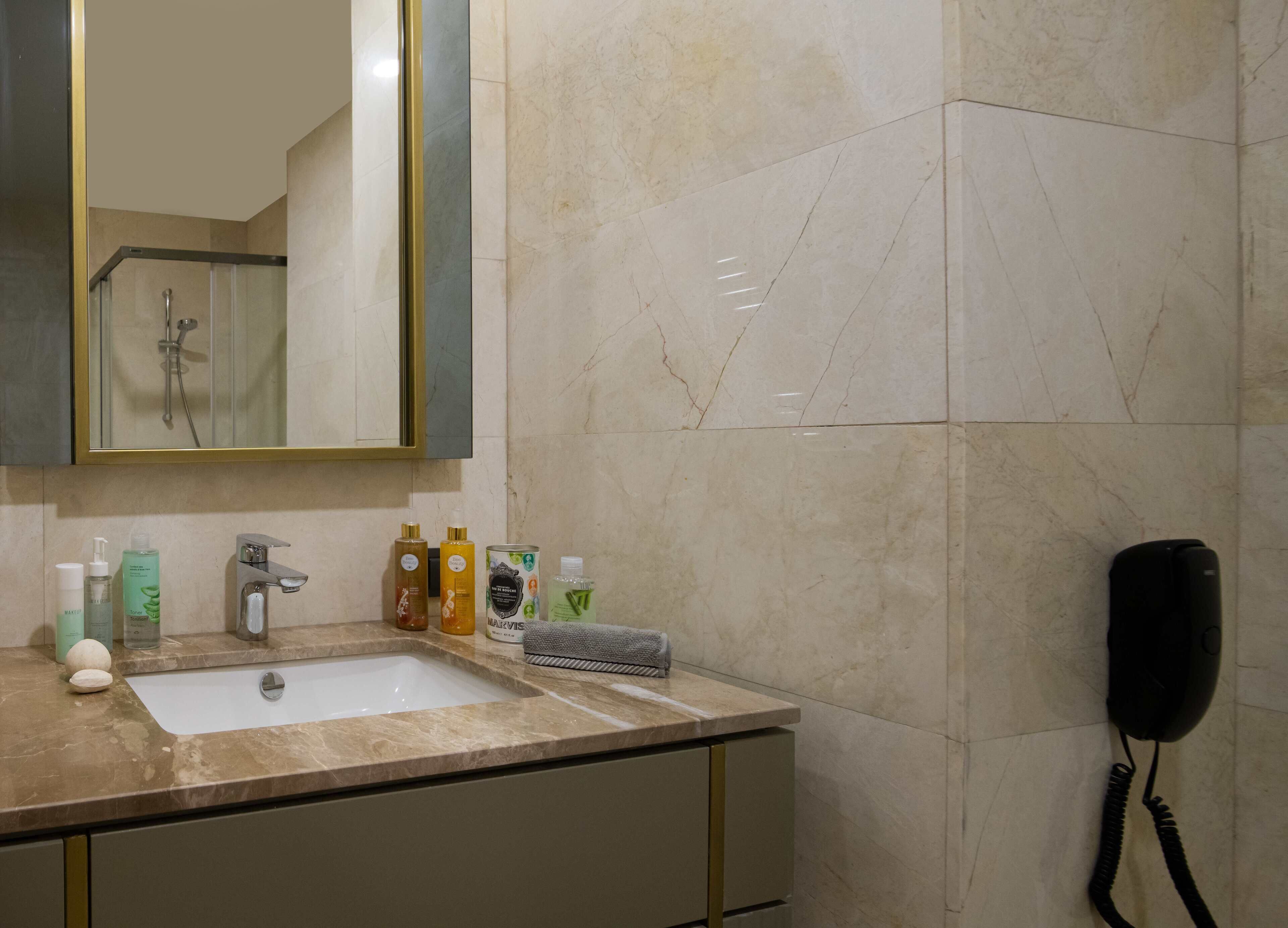 A bathroom with a sink, mirror, toiletries, and a hairdryer.