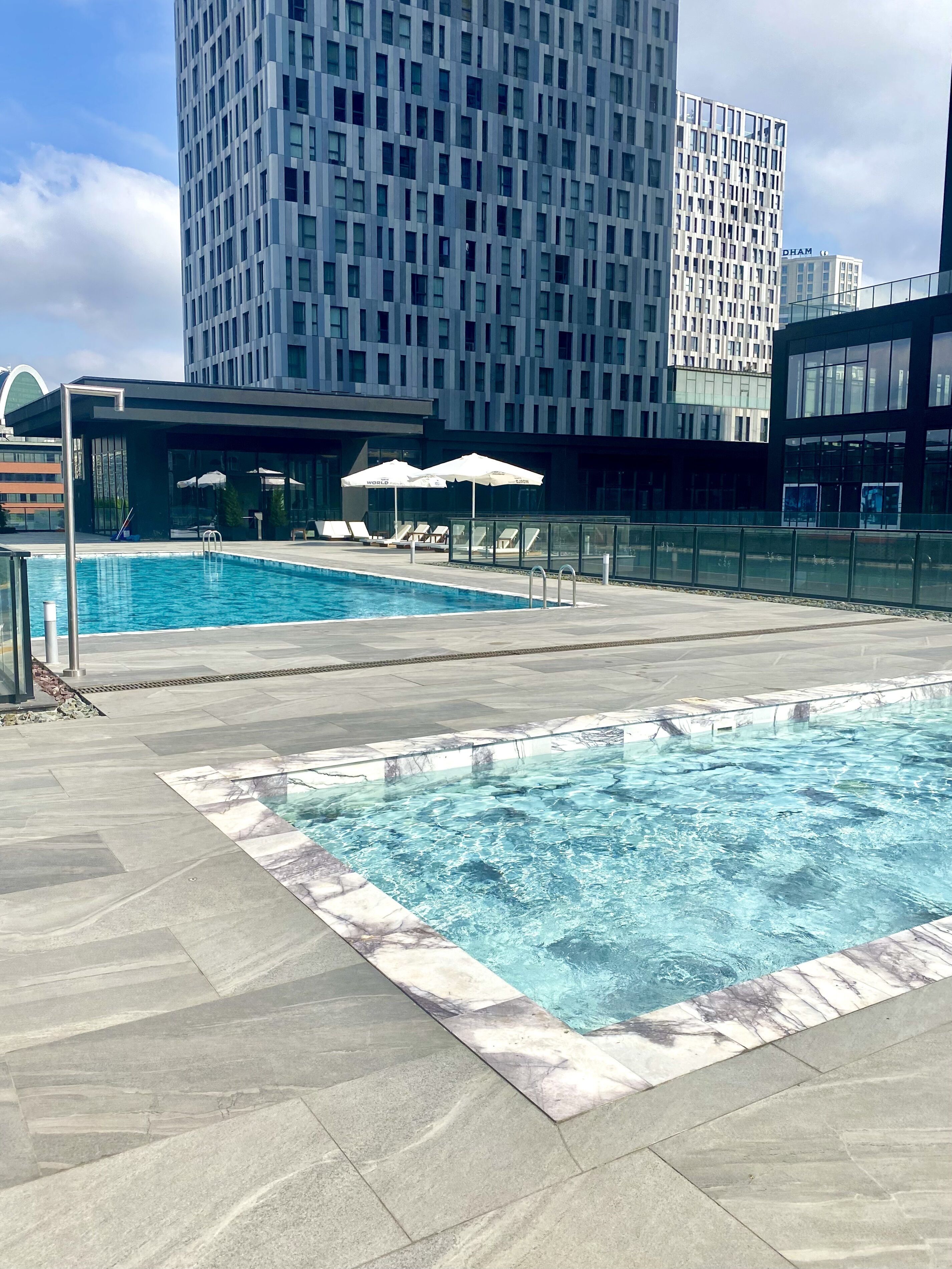 Un espace piscine aménagé sur le toit, avec une eau d’un bleu limpide, des chaises longues et des parasols.