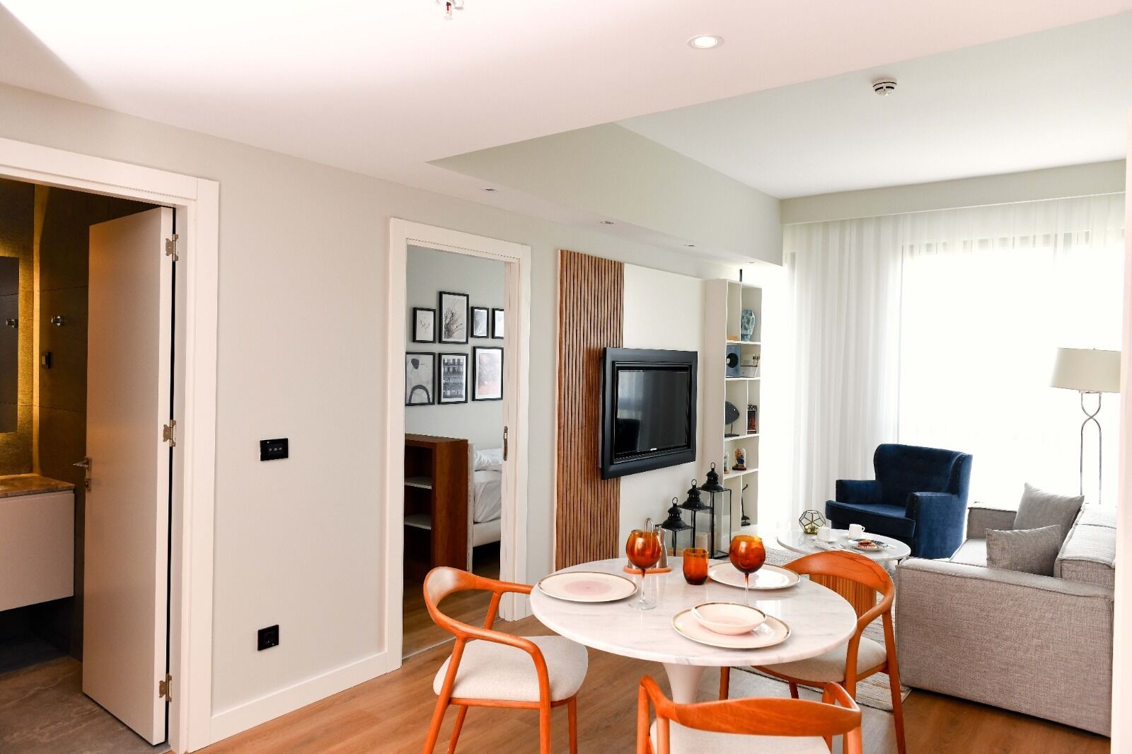 Un salon moderne comprenant un coin repas, un téléviseur fixé au mur et un canapé.