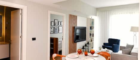 Un salon moderne comprenant un coin repas, un téléviseur fixé au mur et un canapé.