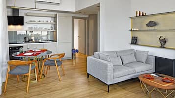 A modern living room with a grey sofa, wooden dining table, and chairs.